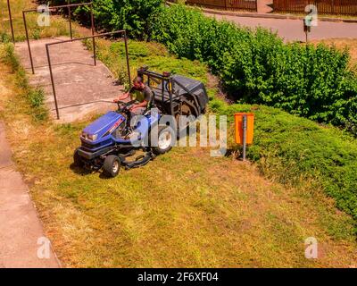 Usti nad Labem / Czech republic - 06.25.2019: A man on a small tractor cutting the grass Stock Photo