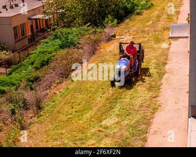 Usti nad Labem / Czech republic - 06.25.2019: A man on a small tractor cutting the grass in front of the residential house Stock Photo