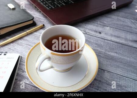 close up of green tea with laptop and office stationary on wooden desk  Stock Photo