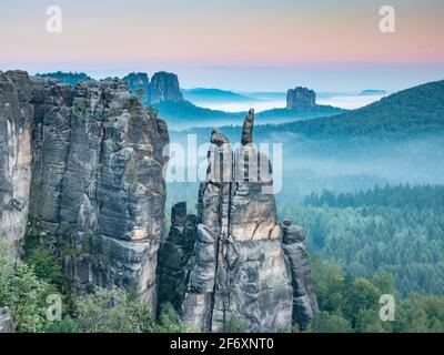 Jagged rocks near Blossstock and Affensteine, in the background the Falkenstein massif in the valley of the evening fog. Stock Photo