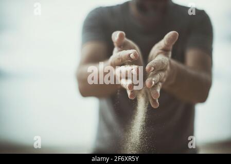 Man standing on the beach with sand running through his hands, Thailand Stock Photo