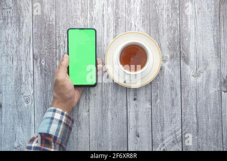 Top view of man hand holding smart phone and drinking tea  Stock Photo