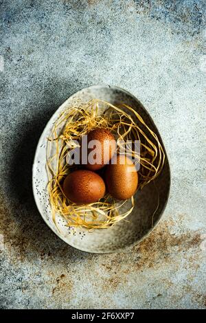 Three eggs in a bowl with straw Stock Photo