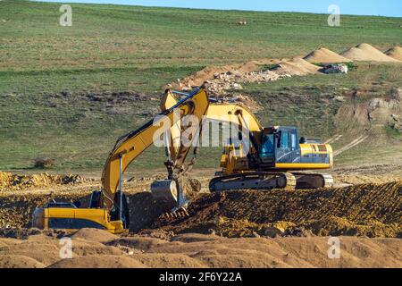 Two excavator during earthmoving at open pit on mountain slope Stock Photo