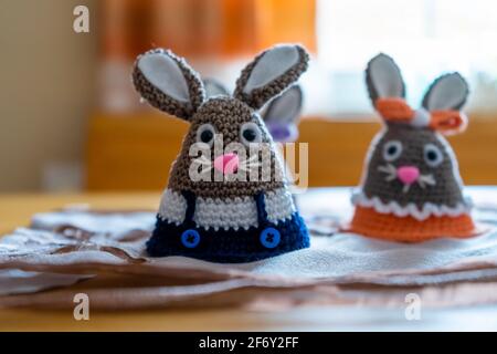 Homemade amigurumi egg warmers crocheted from wool. In different scenes with a white and gray background and on a dining tabl Stock Photo