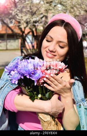 Woman outdoors holding pink and purple flowers Stock Photo