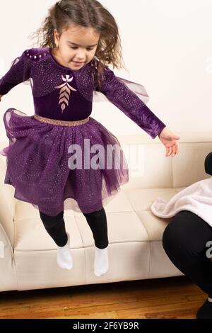 Four year old girl jumping wearing dress up dress Stock Photo