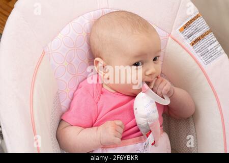 Closeup of two month old baby girl, holding toy, mouthing toy Stock Photo