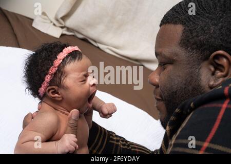 Newborn baby girl 3 weeks old, reflex yawning held by father Stock Photo