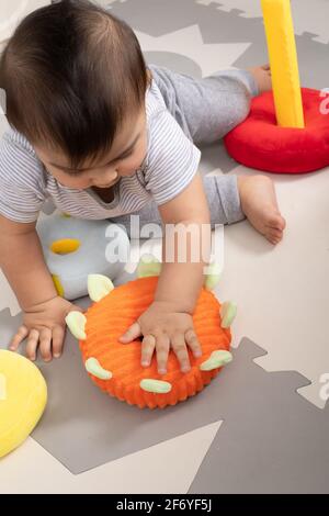 8 month old baby boy sitting playing with cloth rings toy Stock Photo