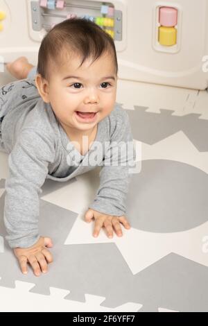 Six month old baby boy portrait smiling looking up to side on stomach pushing up with hands Stock Photo