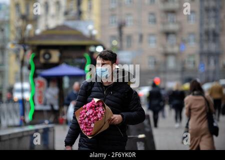 Kiev, Ukraine. 02nd Apr, 2021. A man wearing a mask as a preventive measure against the spread of covid-19 holds a bouquet of flowers while walking along the Streets in Kiev. In Ukraine, as of the morning of April 3, 20,341 new cases of COVID-19 infection were confirmed, which is another record for the number of cases per day. The largest number of confirmed cases over the past day was registered in Kiev, as well as in Lviv, Odessa, Kharkov and Dnepropetrovsk regions. (Photo by Sergei Chuzavkov/SOPA Images/Sipa USA) Credit: Sipa USA/Ģ����ý Live News Stock Photo