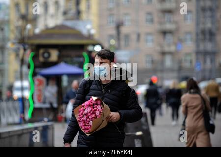 Kiev, Ukraine. 2nd Apr, 2021. A man wearing a mask as a preventive measure against the spread of covid-19 holds a bouquet of flowers while walking along the Streets in Kiev.In Ukraine, as of the morning of April 3, 20,341 new cases of COVID-19 infection were confirmed, which is another record for the number of cases per day. The largest number of confirmed cases over the past day was registered in Kiev, as well as in Lviv, Odessa, Kharkov and Dnepropetrovsk regions. Credit: Sergei Chuzavkov/SOPA Images/ZUMA Wire/Ģ����ý Live News Stock Photo
