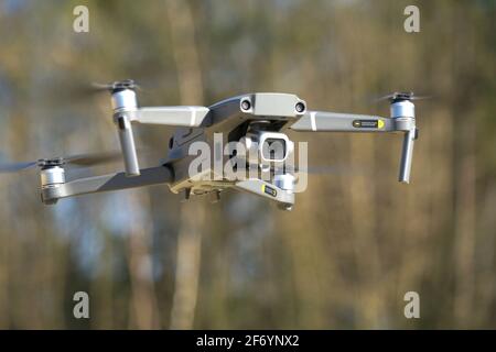 Quadcopter drone hovering before a background of trees Stock Photo