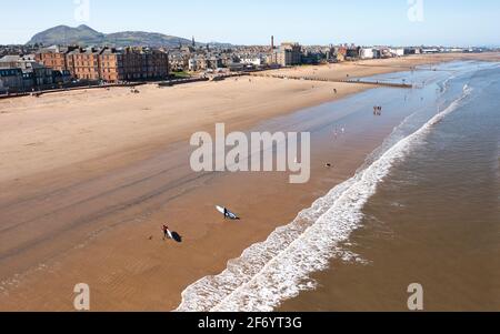 Portobello, Scotland, UK. 3 April 2021. Easter weekend crowds descend on Portobello beach and promenade to make the most of newly relaxed  Covid-19 lockdown travel restrictions and warm sunshine with uninterrupted blue skies. Pic; Aerial drone view of Portobello beach which looks rather quiet at the Eastern end.  Iain Masterton/Alamy Live News Stock Photo