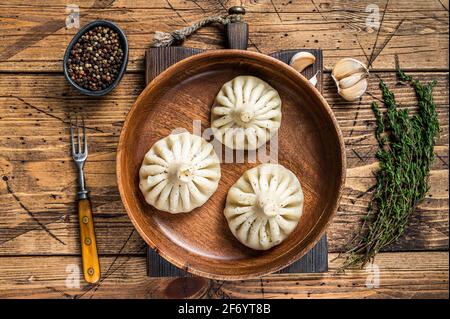 Boiled Khinkali Dumplings with mutton lamb meat in wooden plate. wooden background. Top view Stock Photo