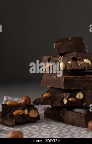 Dark chocolate with almonds and hazelnuts in a stack on brown background Stock Photo