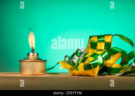 Conceptual traditional Malay oil lamp named pelita with decorative ketupat for Hari Raya Aidilfitri celebration