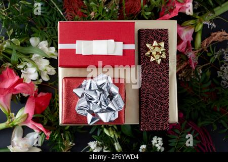 Top view composition with various elegant red colored present boxes with bows placed among blooming flowers Stock Photo