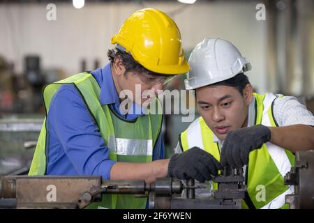 Two workers in production plant as team discussing, industrial scene in background, working together manufacturing activities Stock Photo