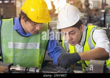 Two workers in production plant as team discussing, industrial scene in background, working together manufacturing activities Stock Photo