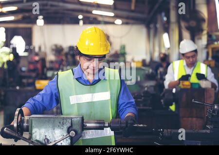 Two workers in production plant as team discussing, industrial scene in background, working together manufacturing activities Stock Photo