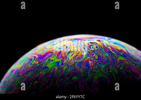Beautiful abstract and various colored soap bubble macro with oval shape with black background and selective focus. Stock Photo