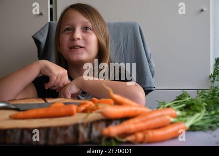 Little girl cuts fresh carrots in the kitchen Stock Photo