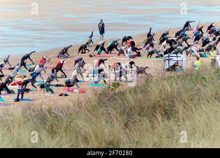 Newquay, Cornwall, England, 3rd  April 2021. UK weather: Cool with sunshine for a mass Yoga class involving 300 plus participants. Silent disco yoga organised by Anthony Durkin DJ in combination with Oceanflow yoga. Fistral beach. Credit: Robert Taylor/Alamy Live News� Stock Photo