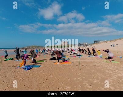 Newquay, Cornwall, England, 3rd  April 2021. UK weather: Cool with sunshine for a mass Yoga class involving 300 plus participants. Silent disco yoga organised by Anthony Durkin DJ in combination with Oceanflow yoga. Fistral beach. Credit: Robert Taylor/Alamy Live News� Stock Photo