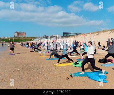 Newquay, Cornwall, England, 3rd  April 2021. UK weather: Cool with sunshine for a mass Yoga class involving 300 plus participants. Silent disco yoga organised by Anthony Durkin DJ in combination with Oceanflow yoga. Fistral beach. Credit: Robert Taylor/Alamy Live News� Stock Photo