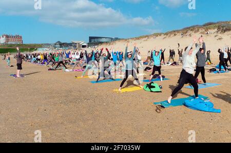 Newquay, Cornwall, England, 3rd  April 2021. UK weather: Cool with sunshine for a mass Yoga class involving 300 plus participants. Silent disco yoga organised by Anthony Durkin DJ in combination with Oceanflow yoga. Fistral beach. Credit: Robert Taylor/Alamy Live News� Stock Photo