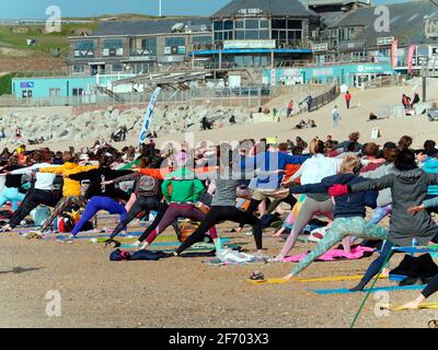 Newquay, Cornwall, England, 3rd  April 2021. UK weather: Cool with sunshine for a mass Yoga class involving 300 plus participants. Silent disco yoga organised by Anthony Durkin DJ in combination with Oceanflow yoga. Fistral beach. Credit: Robert Taylor/Alamy Live News” Stock Photo