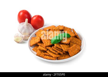 Tomato crackers in a white plate and ingredients garlic and tomatoes in the background, isolated on a white background. The concept of natural healthy Stock Photo