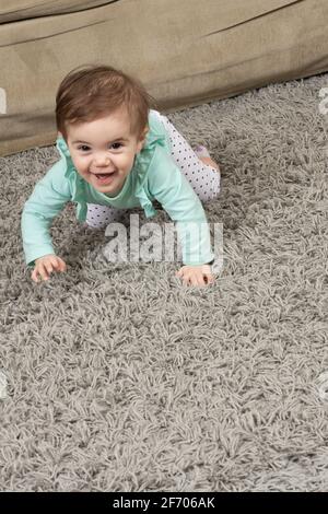 10 month old baby girl crawling on rug at home Stock Photo