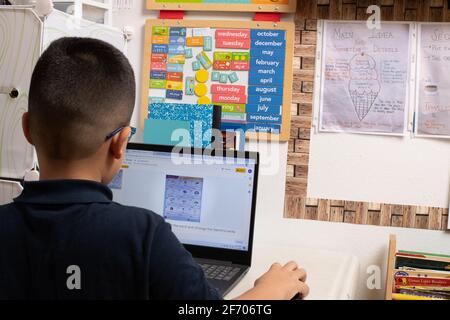 7 year old boy, wearing glasses using laptop computer for school work, learning at home during Covid-19 pandemic shutdown Stock Photo