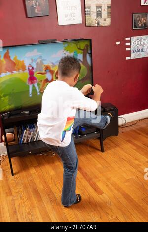 7 year old boy doing dance or physical activity to program on television Stock Photo