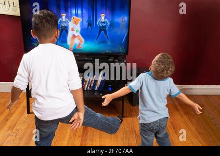 Brothers ages 3 and 7 doing exercise program displaying on TV set Stock Photo