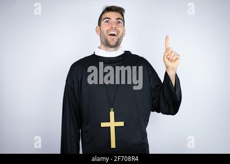 Young hispanic man wearing priest uniform standing over white background Stock Photo