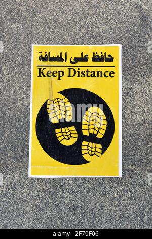 a floor sign in Arabic and English that puts a mark where to stand to keep distance and space between people during the world's pandemic of covid-19 Stock Photo