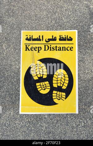 a floor sign in Arabic and English that puts a mark where to stand to keep distance and space between people during the world's pandemic of covid-19 Stock Photo