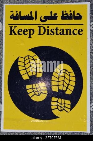 a floor sign in Arabic and English that puts a mark where to stand to keep distance and space between people during the world's pandemic of covid-19 Stock Photo