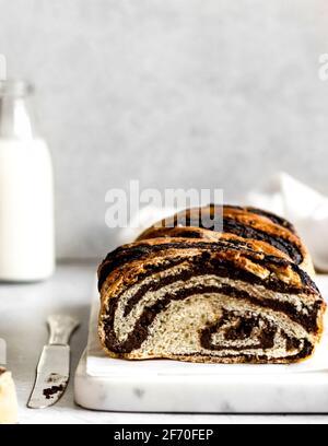 Freshly baked, warm vegan chocolate twist babka lying on a chopping board, ready to be cut and enjoyed as an afternoon dessert. Stock Photo