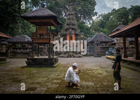 Balinese Hindus bring offerings to the ancient Dalem Agung Padangtegal temple at the Sacred Monkey Forest in Ubud, Bali, Indonesia. Stock Photo