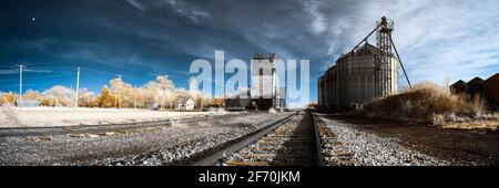 A false color infrared image of a grainery in the tiny prairie community of Athol, South Dakota.  A full moon may be seen rising on the left side. Stock Photo