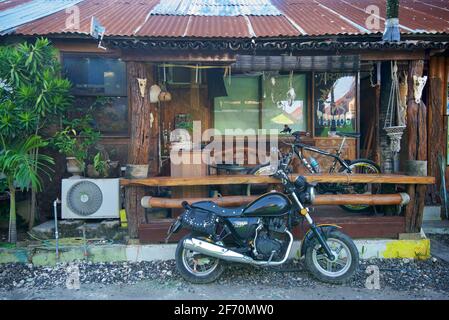 Quirky local residence / Tatoo parlour with a motorcycle parked outside. Moalboal, Cebu island, Philippines. Stock Photo