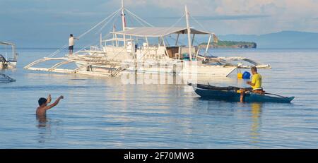 Filipino fisherman in his small outrigger canoe in the Visayan Sea off ...
