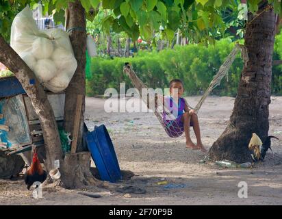 Filipino boy swinging in the warm shade. Malapascua Island, Cebu, the Philippines. Stock Photo
