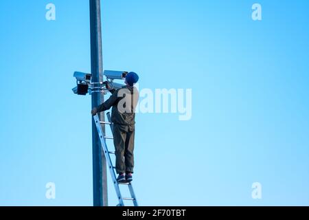 Technician installing security cameras on pole Stock Photo