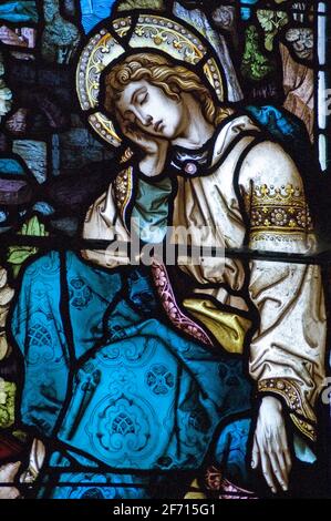 A Victorian stained glass window showing Saint John sleeping under the cross where Jesus Christ is being crucified.  Window over 100 years old.